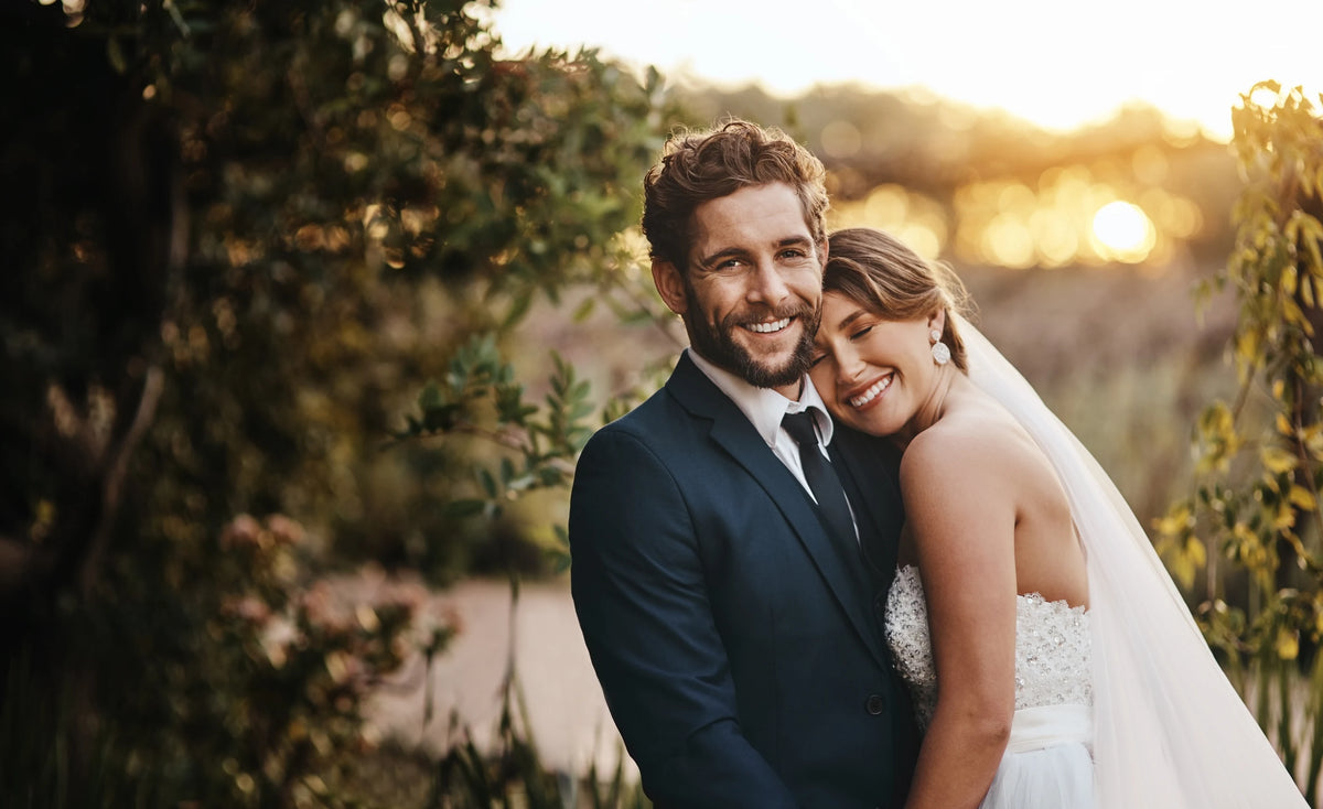 Smiling newlywed couple embracing outdoors in warm evening light